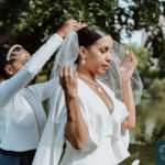 a photo of the daughter of the bride helping the bride out on her veil. small wedding ceremony.