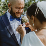 a closeup of the groom smiling as the bride puts on his boutonniere. Small wedding in central park.