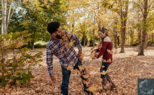 Newly engaged couple playing in the fall foliage.