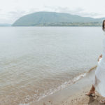 closeup of the bride in her wedding dress by the water.