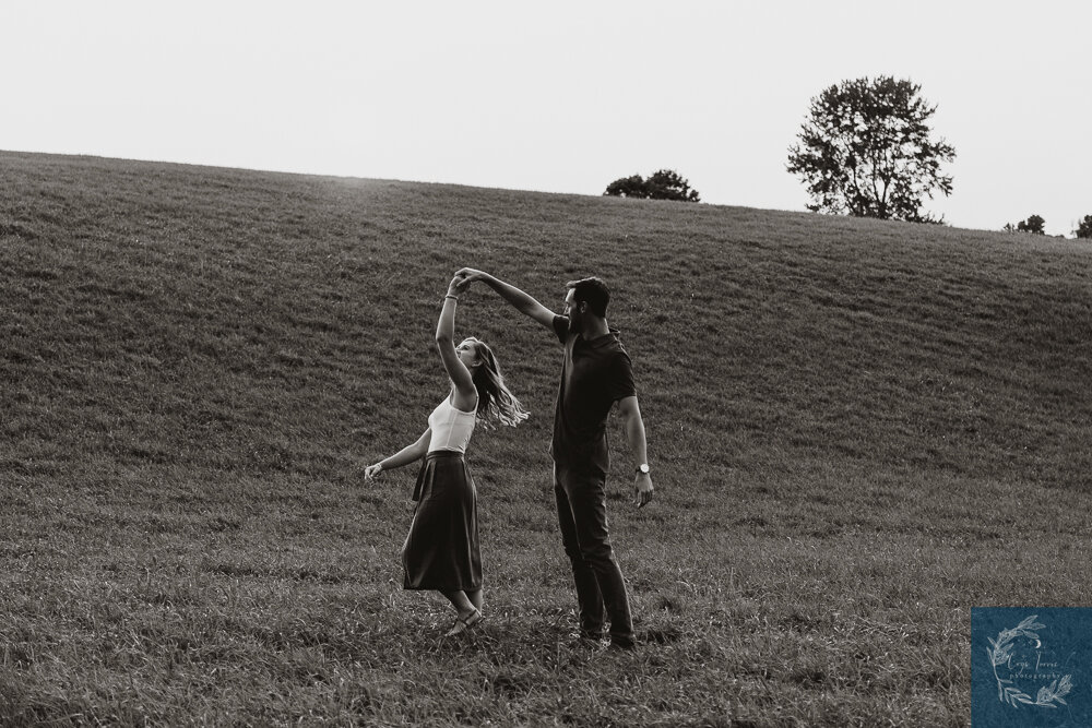 Engagement sessions and why they are so important. Newly engaged couple dances together on a hill.