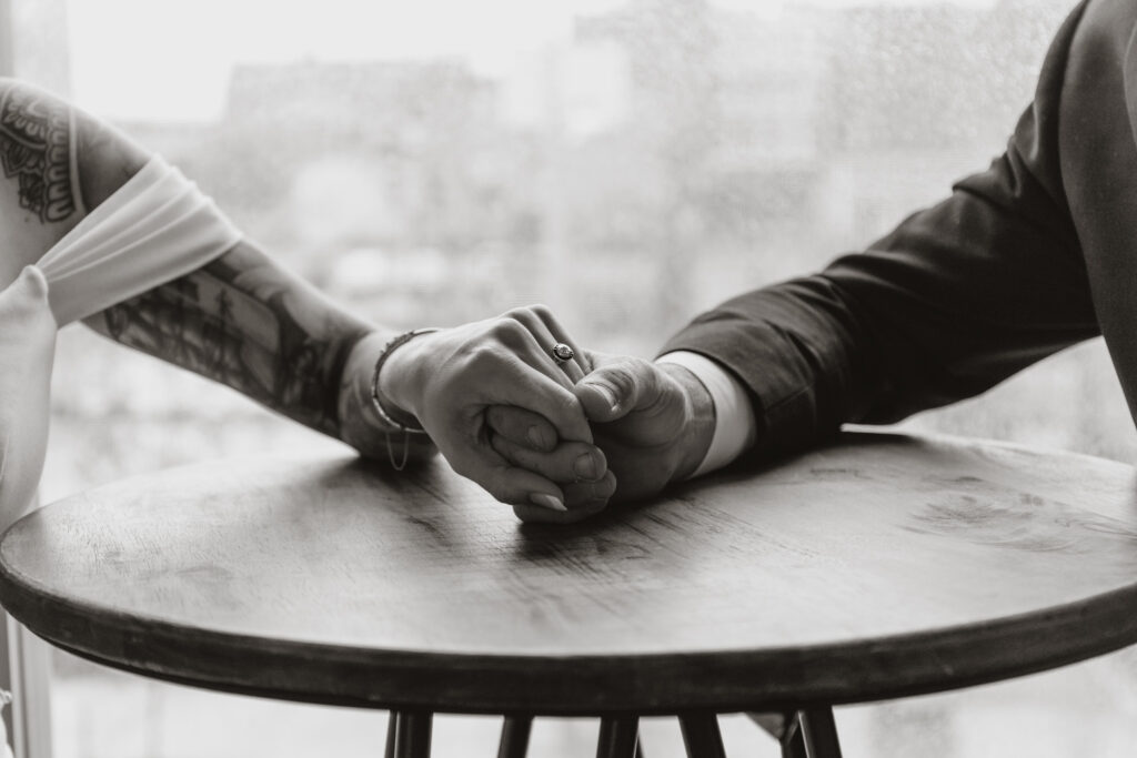 black and white shot close up couple holding hands.